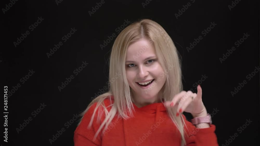 Portrait of young white-haired caucasian girl in red sweater strangely dancing and singing on black background. Portrait of young white-haired caucasian girl in red sweater strangely dancing and singing on black background.