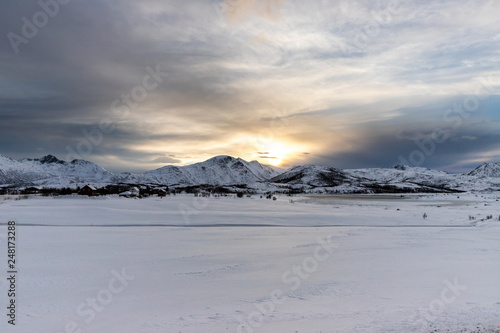 frozen lake and snow-covered mountains at sunset, Lofoten Islands, Norway