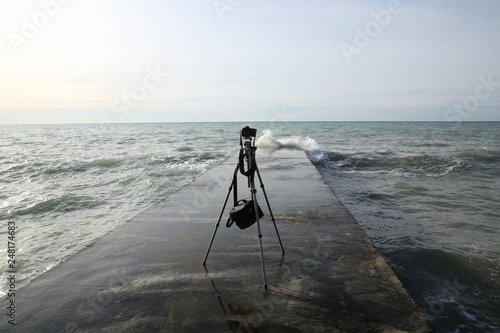 tripod with a camera is standing on the breakwater in the sea without a photographer