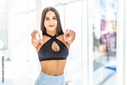Photo of beautiful sports woman trainer standing and posing in gym while pointing and looking at camera. © F8  \ Suport Ukraine