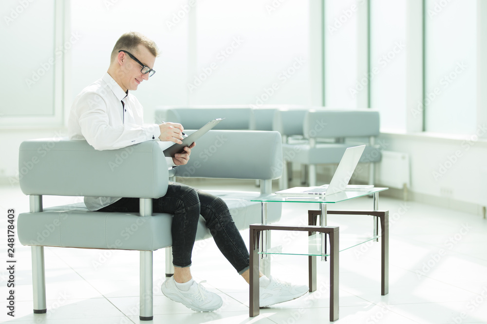 businessman sitting in the office lobby and reading a business document businessman sitting in the office lobby and reading a business document