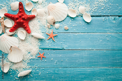 summer background red starfish and seashells on blue wooden background photo