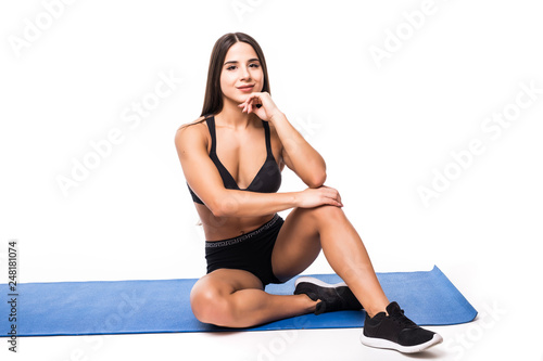 Portrait of a smiling fitness woman resting while sitting and looking at camera isolated over white background