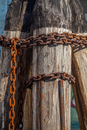 Pier wooden poles tightened together by rusty chains on canal in Venice, Italy