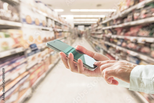 Digital lifestyle business person or shopper using mobile smart phone for retail shopping in supermarket