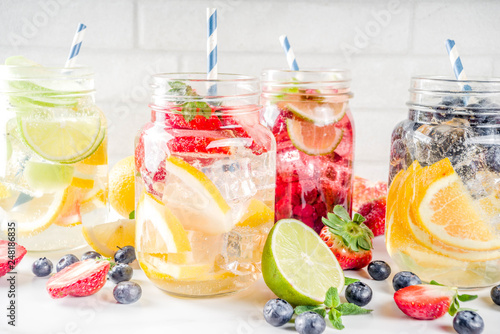 Selection various fruit and berry lemonade drinks, refreshment infused water, in mason jars, with fresh strawberry, lemon, lime, oranges, blueberry, copy space
