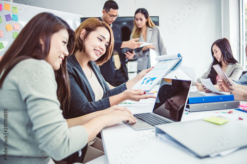 Businesswoman presenting to colleagues at a meeting.Successful team leader and business owner leading informal in-house business meeting. Businessman working on laptop in foreground. © Yingyaipumi