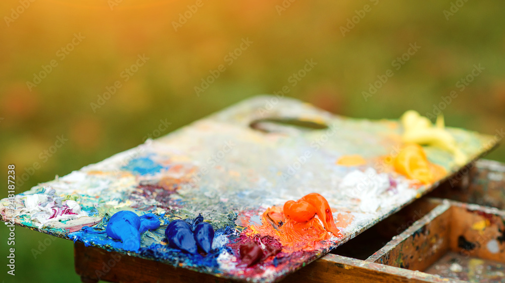 Acrylic colors on a dirty palette. Macro artist's palette. Artist paints a picture of oil paints. Wooden art palette with paint and brushes, close up. Art therapy.