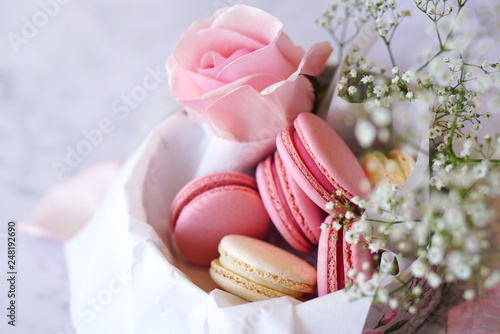 Beautiful colourful macarons with flowers in round paper box, closeup   