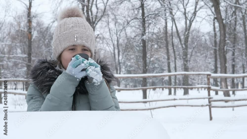 Hot drink in the winter in nature. Little girl drinks a hot drink in the winter outdoors. Hot drink in the winter in nature. Little girl drinks a hot drink in the winter outdoors.