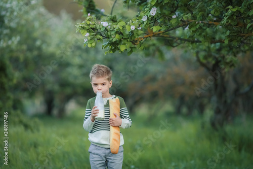 Canvas Print Cute child drinking milk outdoors. Cheerful boy on the picnic