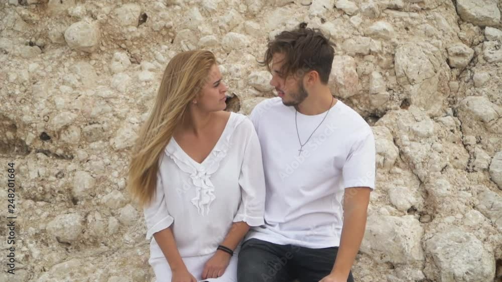 Young beautiful couple stand near big rocks and talking Young beautiful couple stand near big rocks and talking