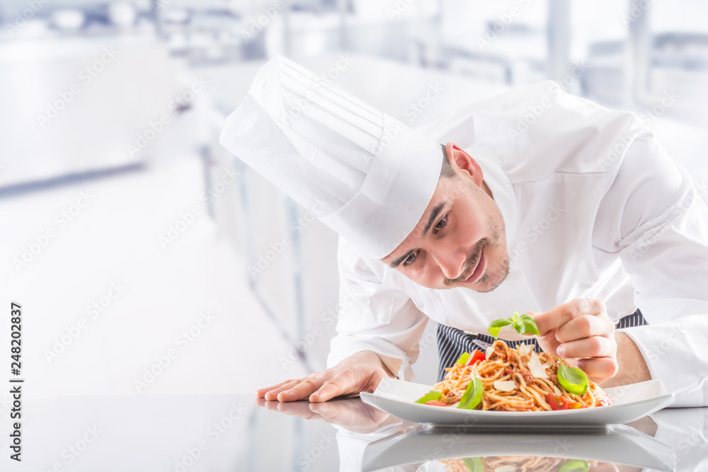 Chef in restaurant kitchen prepares and decorates meal with hands. Cook preparing spaghetti bolognese Chef in restaurant kitchen prepares and decorates meal with hands. Cook preparing spaghetti bolognese