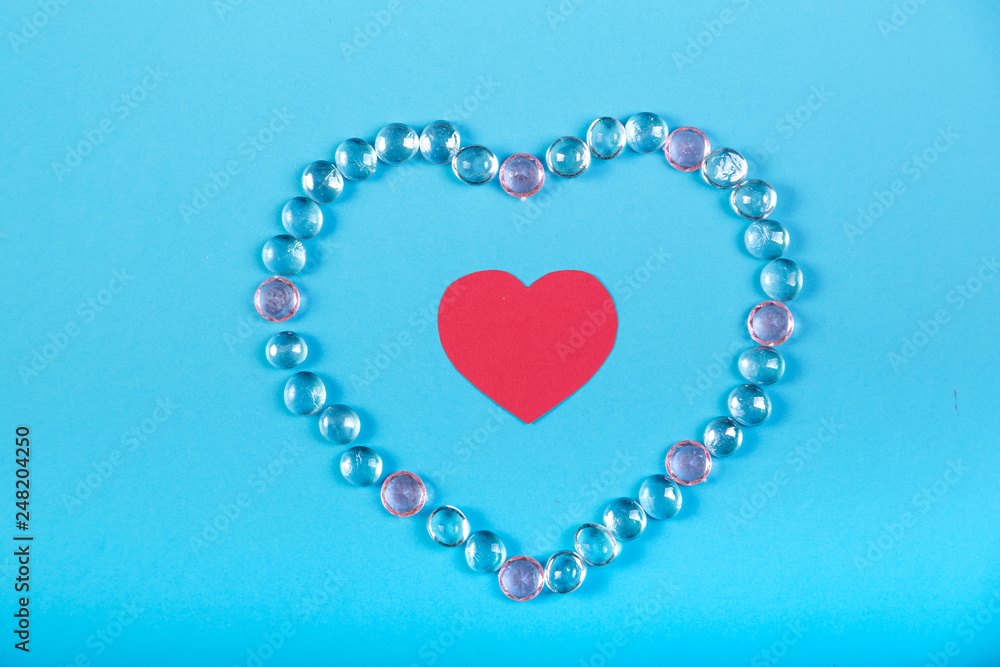 The heart of white beads and a red heart in the middle on a blue background.