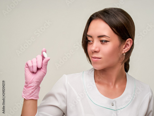 Doctor holds a pill. Hand in pink Gloves with Pill. Doctor works in a clinic. Healthcare concept