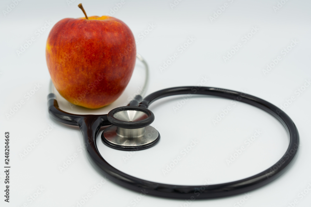 Black stethoscope and red apple on white background Black stethoscope and red apple on white background
