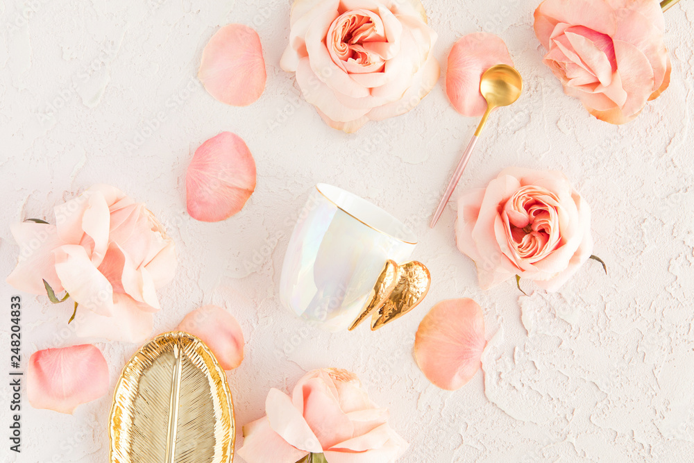 Stylish coffee or tea set on pastel background with pink flowers, leaf golden plate and spoon with roses and petals. Flatlay, top view on pastel concrete background Stylish coffee or tea set on pastel background with pink flowers, leaf golden plate and spoon with roses and petals. Flatlay, top view on pastel concrete background