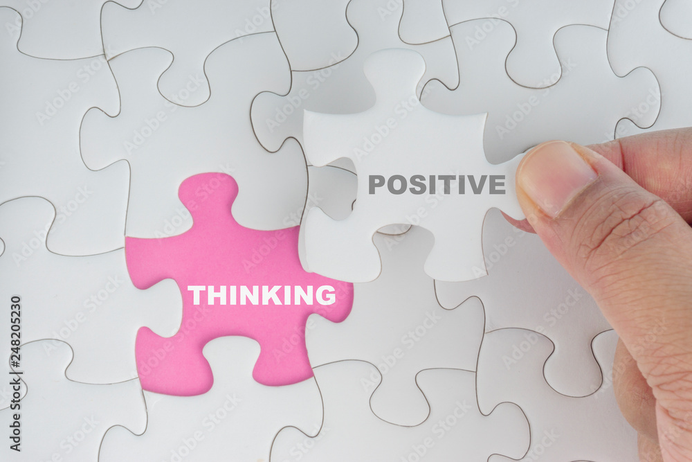 Fototapeta premium Hand holding piece of jigsaw puzzle with word POSITIVE THINKING. Selective focus