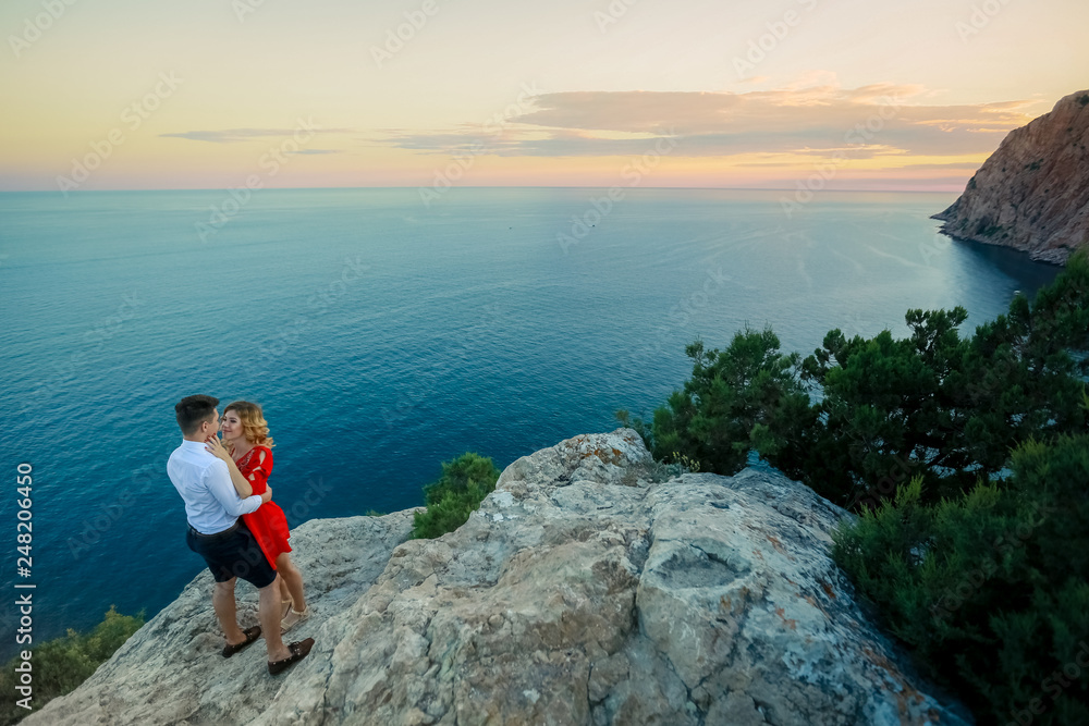 Naklejka premium Couple family traveling together on cliff edge in Norway man and woman lifestyle concept summer vacations outdoor aerial view Lofoten islands Reinebringen mountain top