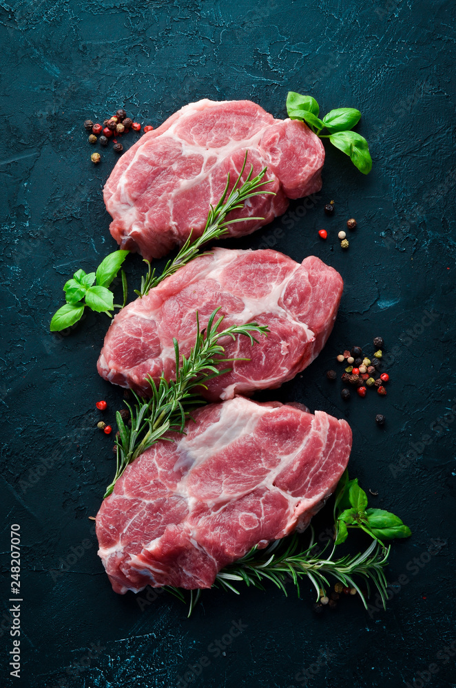 Raw steak. Meat with spices and herbs. On a black stone background. Top view. Free copy space.