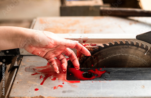 Hand and circular saw disc bloody on white background