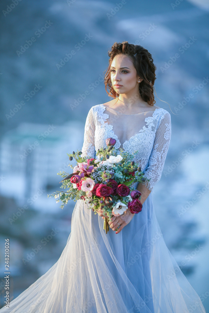 Beautiful bride in fashion wedding dress on natural background.The stunning young bride is incredibly happy. Wedding day. .A beautiful bride portrait at sea view