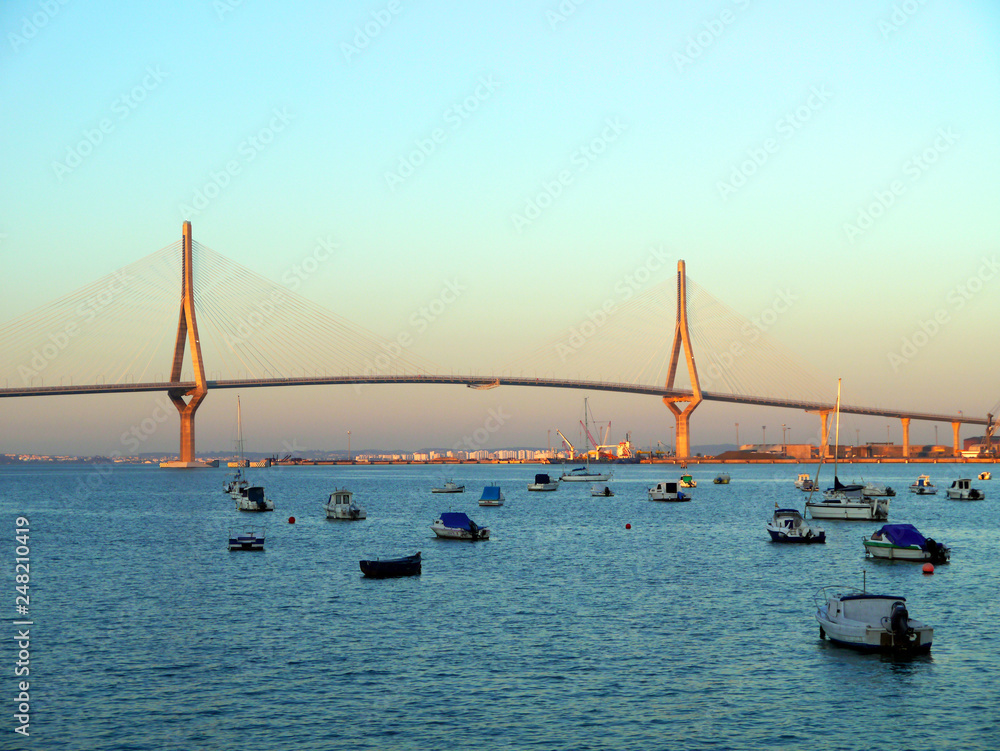 Obraz premium Fishing boats in sunset at the Puente de la Constitución, called La Pepa, in the bay of Cádiz, Andalusia. Spain