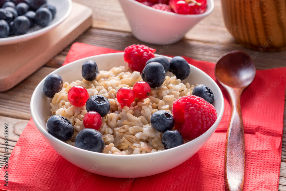 Close up view of porridge with blueberries and raspberries and grain bread on wooden background. Healthy breakfast. Close up view of porridge with blueberries and raspberries and grain bread on wooden background. Healthy breakfast.