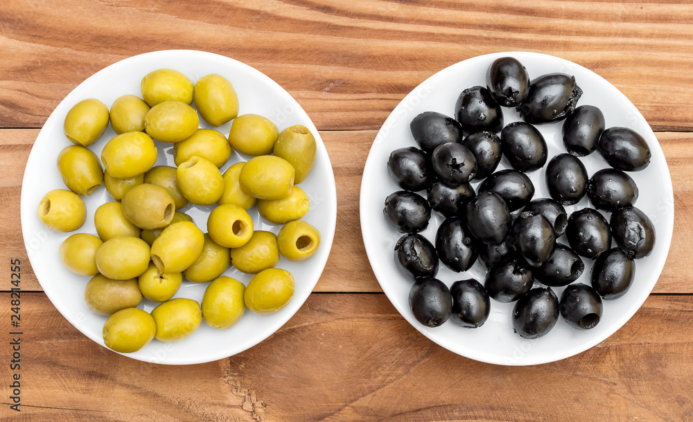Saucers with black and green olives on wooden table. Top view. Saucers with black and green olives on wooden table. Top view.