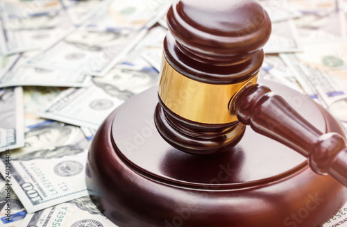 Judge's gavel on background of dollar bills.