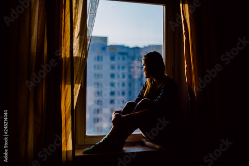 Fotografie Portrait of Beautiful Thoughtful Woman Relaxing on a Window Sill in the Backgrou