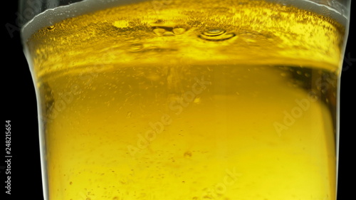 Beer is poured into a glass, on the wall foam flows on a black background, slow-motion shooting, Oktoberfest