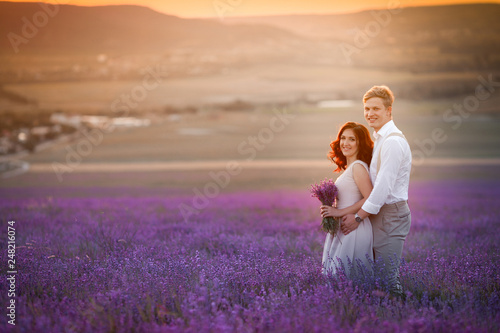 Young couple in love bride and groom, wedding day in summer. Enjoy a moment of happiness and love in a lavender field. Bride in a luxurious wedding dress.