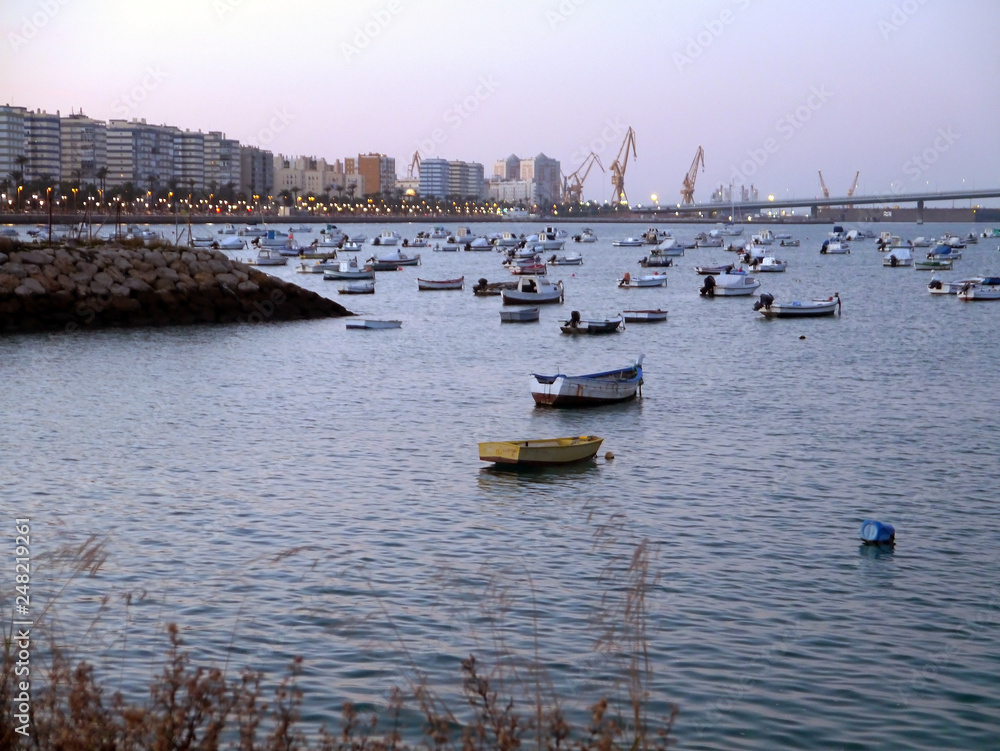 Fototapeta premium Fishing boats in sunset at the Puente de la Constitución, called La Pepa, in the bay of Cádiz, Andalusia. Spain