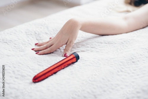 Young woman’s hand reaching for sex toy dildo photo