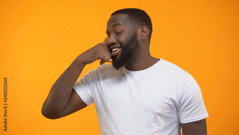 Handsome Afro-American man showing call me gesture, customer services, feed back Handsome Afro-American man showing call me gesture, customer services, feed back