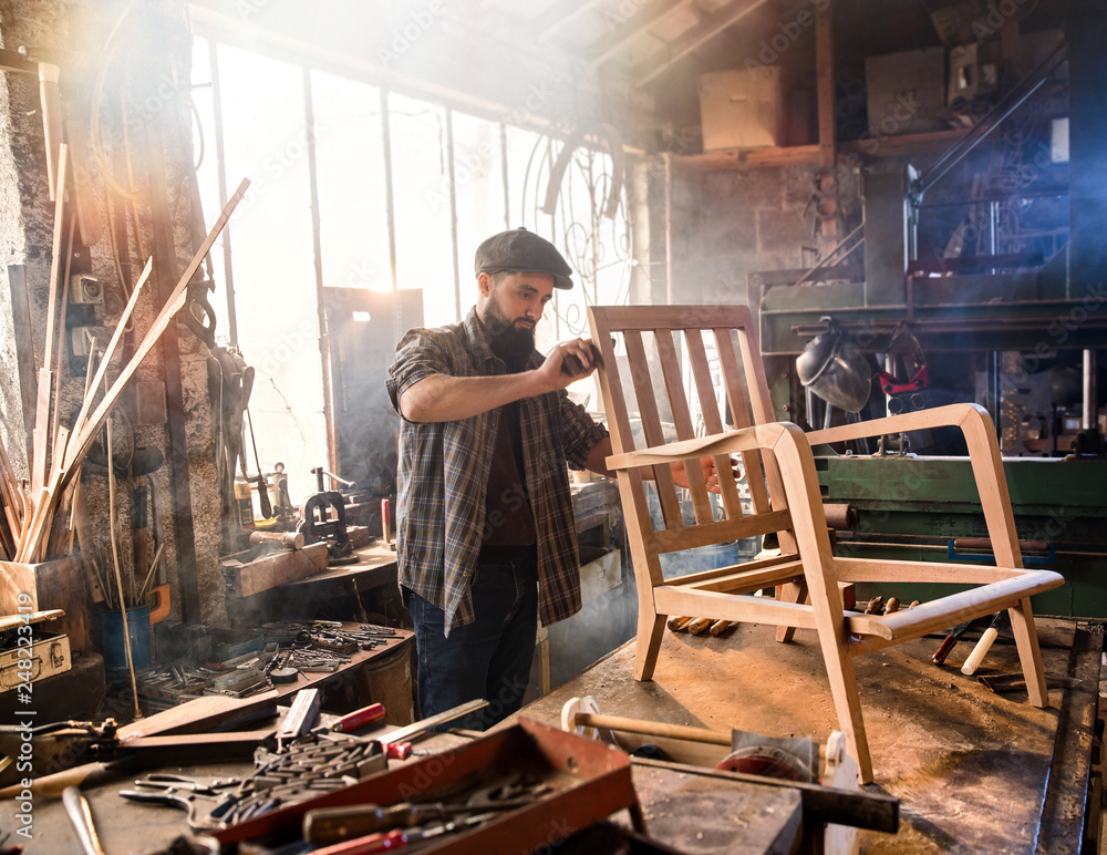 A craftsman in his workshop working on an armchair frame A craftsman in his workshop working on an armchair frame