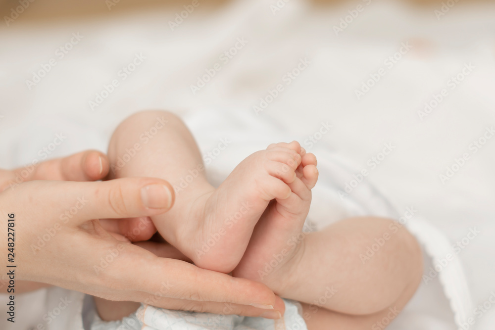 mother's hands gently hold the feet of a newborn baby in the palms mother's hands gently hold the feet of a newborn baby in the palms