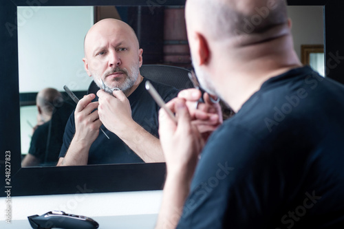 A man is cutting a beard wi...