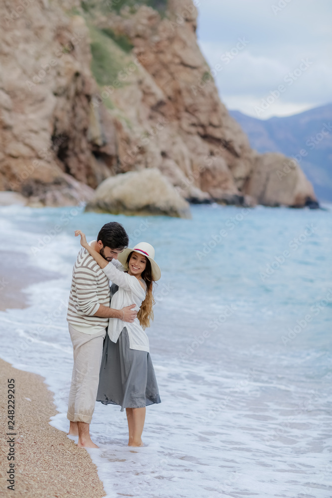 Romantic atmosphere. Happy couple woman and man walking the dog near the sea with mountains in the background. Romantic atmosphere. Happy couple woman and man walking the dog near the sea with mountains in the background.