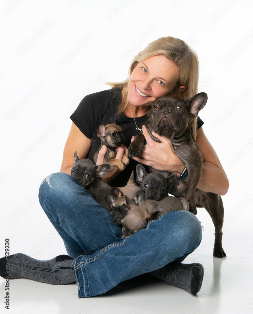 Woman sitting, holding her French Bulldog puppies and mom Woman sitting, holding her French Bulldog puppies and mom