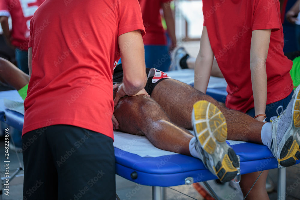 Athlete lying on a Bed while having Legs Massaged after a Physical Sports Workout