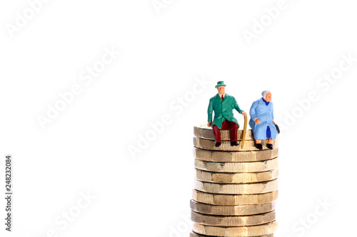 Conceptual diorama image of a miniture figure retired couple sat on a stack of pound coins