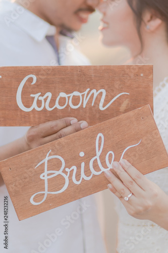 Close up of the bride and groom holding sign wooden plate outdoors. Romantic couple and love concept