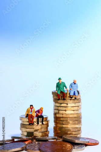 Conceptual diorama image of a miniture figure retired couple and young couple sat on a stack of pound coins
