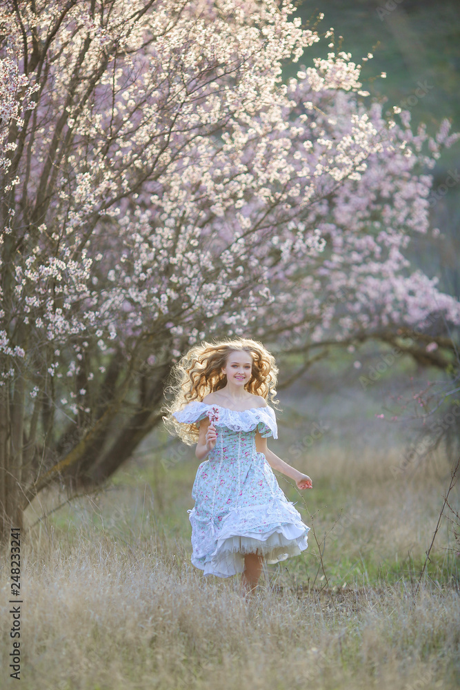 Sweet woman in a beautiful dress, walking through the park with flowers in hands Sweet woman in a beautiful dress, walking through the park with flowers in hands
