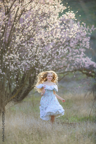 Sweet woman in a beautiful dress, walking through the park with flowers in hands © ElenaBatkova