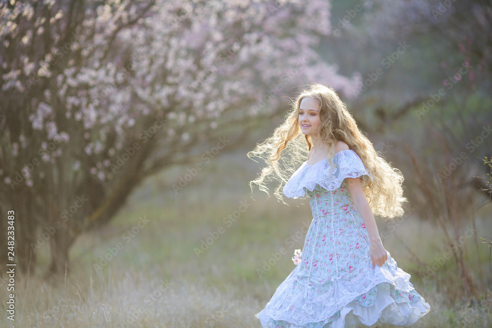 Sweet woman in a beautiful dress dancing in a park with long hair
