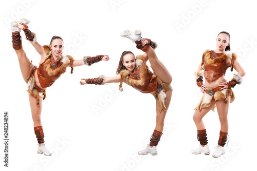 cheerleader dressed in a warrior costume stands in vertical splits, girl doing acrobatic and flexible tricks, dancer practicing mixed dance and stretching, extending leg up, vertical twine, image set