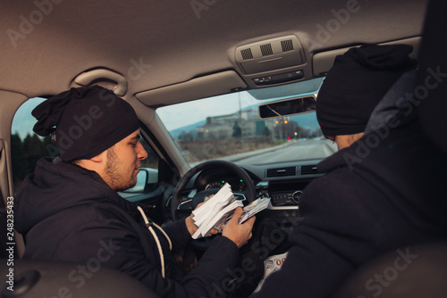 Two happy bank robbers celebrating their successful hit while sitting in the car they used for the robbery.